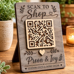 May include: A rectangular gray wooden sign with a stand featuring the engraved text SCAN TO SHOP at the top and Proon & Ivy CUSTOM GIFTS & HOME DECOR at the bottom. A light-colored wooden QR code is mounted in the center with a small heart icon below.