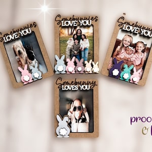 Peut inclure: Quatre cadres photo en bois avec le texte "Somebunnies Love You" et "Somebunny Loves You". Chaque cadre a une d&eacute;coupe de lapin en bas. Les lapins sont de couleurs pastel : rose, bleu, violet et blanc. Les cadres contiennent des photos de famille.