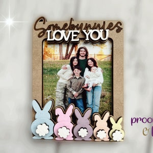 Peut inclure: Un cadre photo en bois avec l'inscription "Somebunnies LOVE YOU" en &eacute;criture cursive. Le cadre a une ouverture rectangulaire pour une photo et est d&eacute;cor&eacute; de d&eacute;coupes de lapins aux couleurs pastel en bas. Le cadre est de couleur marron clair.