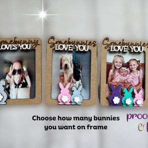 Peut inclure: Trois cadres photo en bois avec les textes "Somebunny Loves You" et "Somebunnies Love You". Chaque cadre a une d&eacute;coupe de lapin en bas de diff&eacute;rentes couleurs. Les cadres contiennent des photos de personnes et d'animaux.