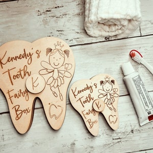 May include: Two wooden tooth fairy boxes shaped like teeth with a fairy and the text "Kennedy's Tooth Fairy Box" and a letter "K" on each.