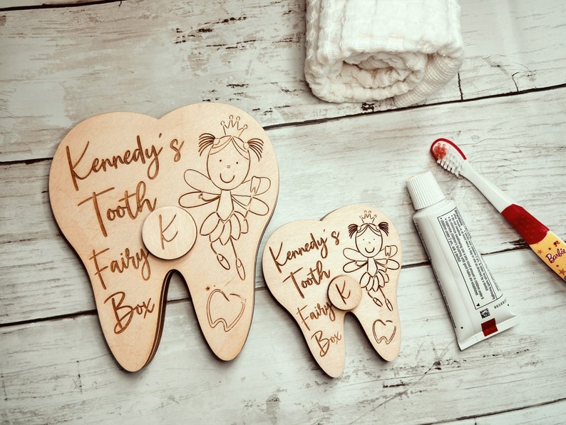 May include: Two wooden tooth fairy boxes shaped like teeth with a fairy and the text "Kennedy's Tooth Fairy Box" and a letter "K" on each.