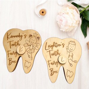 May include: Two wooden tooth fairy boxes shaped like teeth. The box on the left has a fairy with wings and a crown, and the text "Kennedy's Tooth Fairy Box" with the letter "K" on a circle. The box on the right has a boy with a crown and the text "Leighton's Tooth Fairy Box" with the letter "L" on a circle.