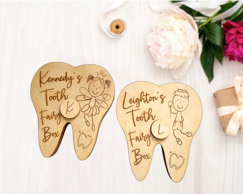 May include: Two wooden tooth fairy boxes shaped like teeth. The box on the left has a fairy with wings and a crown, and the text "Kennedy's Tooth Fairy Box" with the letter "K" on a circle. The box on the right has a boy with a crown and the text "Leighton's Tooth Fairy Box" with the letter "L" on a circle.