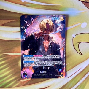 Può includere: Una carta collezionabile con Sanji della ciurma di Cappello di Paglia. La carta ha una valutazione di potenza d'attacco di 5000 e include il testo del gioco. L'artwork raffigura Sanji in abito nero, con capelli biondi e una sigaretta.