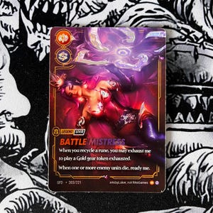 Op de afbeelding: Een ruilkaart met een fantasie-illustratie van een vrouw in rode en paarse kleding. De kaart is gelabeld "BATTLE MISTRESS" met speltekst en een kaartnummer. De achtergrond is een zwart-wit patroonstof.