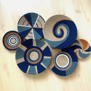 May include: Six woven wall decor pieces in various blue, brown, and white patterns. The pieces are circular and have a natural fibre texture.