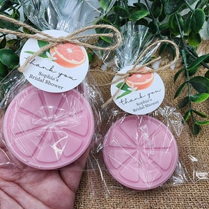 May include: Two clear cellophane bags with pink grapefruit-shaped soaps and thank you tags. The tags are round and white with a grapefruit illustration and the text "Thank you, Sophia's Bridal Shower".