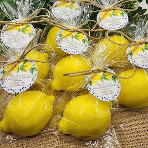 May include: Yellow lemon-shaped soaps wrapped in clear cellophane bags with a blue and white patterned tag that says "Thank you for coming to celebrate with us Camilo Jose 1st Birthday!"