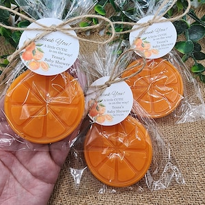 May include: Orange-shaped favors with a white tag that reads "Thank You! A little CUTIE is on the way! Tessa's Baby Shower 06/01/24".