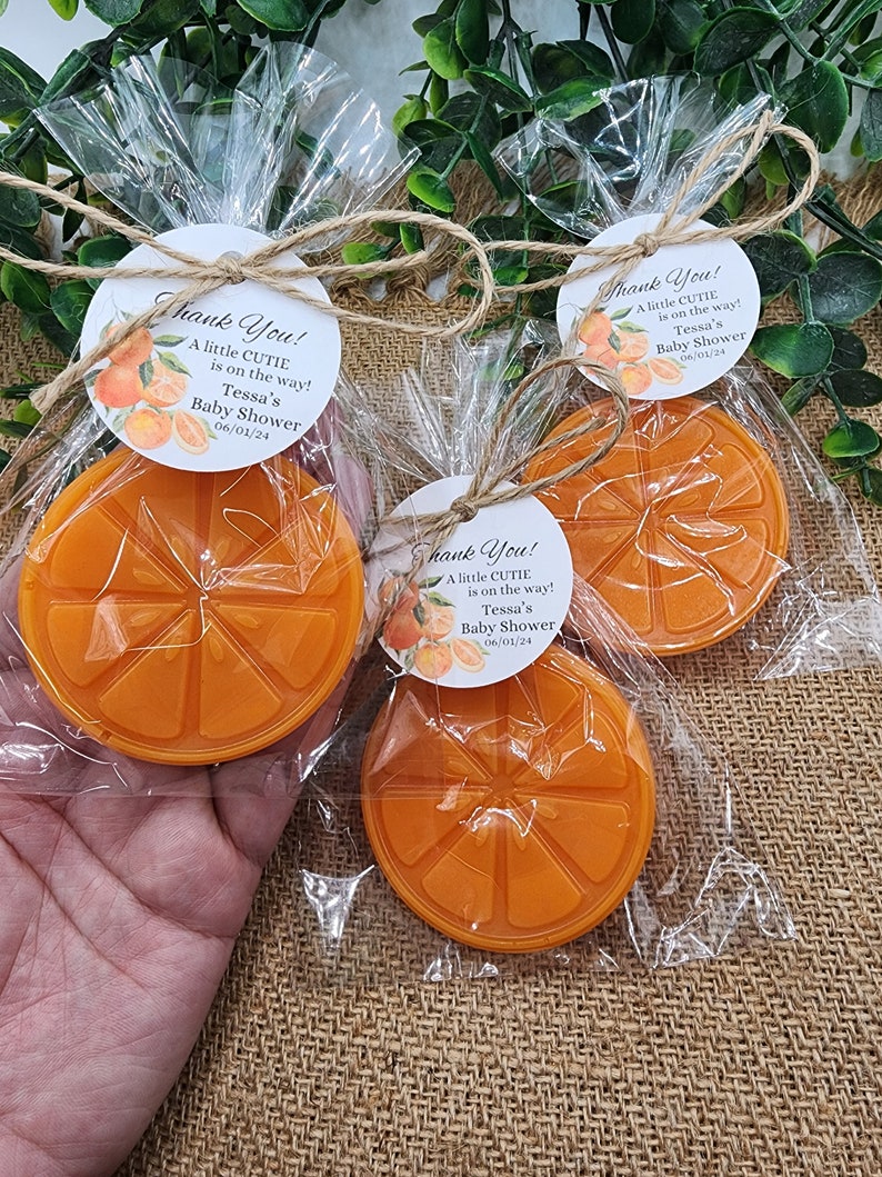 May include: Orange-shaped favors with a white tag that reads "Thank You! A little CUTIE is on the way! Tessa's Baby Shower 06/01/24".
