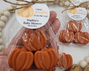 May include: Orange pumpkin-shaped favors in clear cellophane bags, tied with twine and a circular tag. The tag reads "A little pumpkin is on the way!" and "Sophia's Baby Shower 09.20.2025". The favors are for a baby shower.
