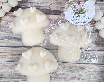 May include: Three mushroom-shaped soaps with heart accents. One soap is wrapped in clear cellophane with a tag that reads "Thank you fairy much Love, Sophia". The soaps are white and sit on a wooden surface.