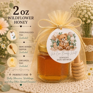 May include: A 2 oz jar of wildflower honey inside a gold organza bag with a wooden honey dipper. A round tag features a teddy bear illustration and the text We Can Bearly Wait Sophia's Baby Shower. The set includes a personalized tag and bag.