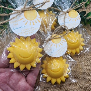 May include: Yellow sun-shaped favours with a smiling face, packaged in clear cellophane bags with a tag that reads "Here comes the sun. Thank you for brightening our day!"