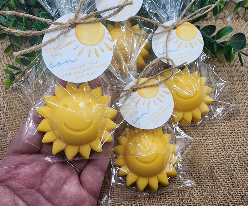 May include: Yellow sun-shaped favours with a smiling face, packaged in clear cellophane bags with a tag that reads "Here comes the sun. Thank you for brightening our day!"