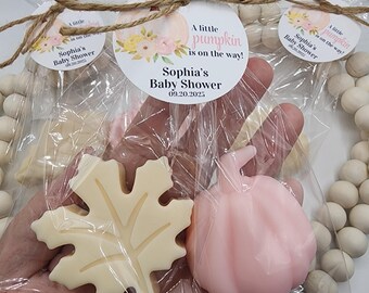May include: Baby shower favors in clear cellophane bags. Each bag contains a leaf-shaped and a pumpkin-shaped soap. The bags are tied with twine and a circular tag that reads "A little pumpkin is on the way!" and "Sophia's Baby Shower 09.20.2025."