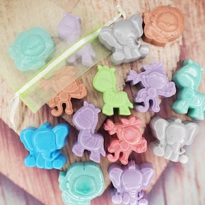 May include: A set of 12 colorful animal-shaped soaps, including elephants, zebras, lions, and monkeys. The soaps are arranged in a heart-shaped pattern on a wooden surface.