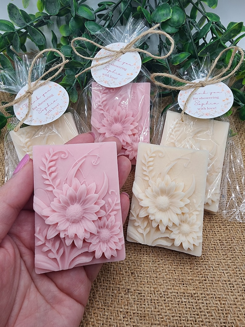 Puede incluir: Tres jabones peque&ntilde;os, rectangulares, con estampado floral envueltos en celof&aacute;n transparente con cuerda y una etiqueta redonda que dice "&iexcl;Gracias por celebrar a Sophia con amor!"