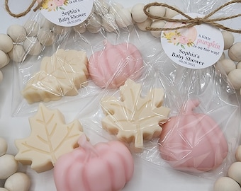 May include: Baby shower favors featuring pumpkin and leaf-shaped soaps in clear cellophane bags. The soaps are in shades of cream and pink. Each bag has a tag that reads "A little pumpkin is on the way! Sophia's Baby Shower 09.20.2025".
