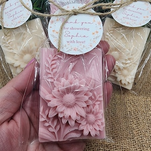 Puede incluir: Pastilla de jab&oacute;n floral rosa envuelta en celof&aacute;n con una etiqueta redonda de agradecimiento que dice "&iexcl;Gracias por celebrar a Sophia con amor!"