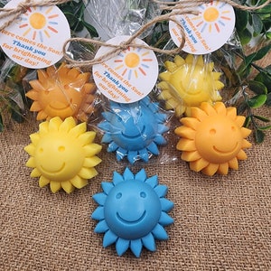 May include: Assortment of small, colourful, sun-shaped soaps with smiley faces. The soaps are packaged in clear cellophane bags with a tag that reads "Here comes the Son! Thank you for brightening our day!"