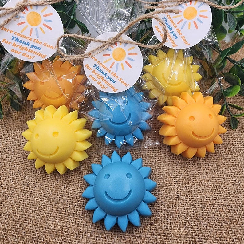 May include: Assortment of small, colourful, sun-shaped soaps with smiley faces. The soaps are packaged in clear cellophane bags with a tag that reads "Here comes the Son! Thank you for brightening our day!"