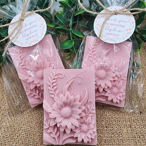 Puede incluir: Tres favores de jab&oacute;n floral rosa envueltos en bolsas de celof&aacute;n transparentes atadas con cuerda y una peque&ntilde;a etiqueta redonda que dice "&iexcl;Gracias por celebrar a Sophia con amor!"