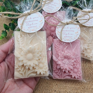 Puede incluir: Tres peque&ntilde;as barras de jab&oacute;n envueltas con dise&ntilde;os florales. Cada barra tiene una etiqueta redonda adjunta con el texto "&iexcl;Gracias por celebrar a Sophia con amor!" en letras rosas.