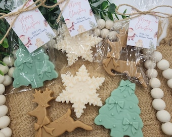 May include: Christmas-themed soaps in the shapes of snowflakes, Christmas trees, and reindeer. Each soap is a different color, including green, beige, and brown. The soaps are packaged in clear cellophane bags and tied with twine, with a tag that reads "Merry Christmas".