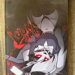 May include: A comic book cover featuring a stylized illustration of a character with white fur and red accents. The title "LOONA COMIC" is in red, stylized lettering. The background is dark with other character illustrations.