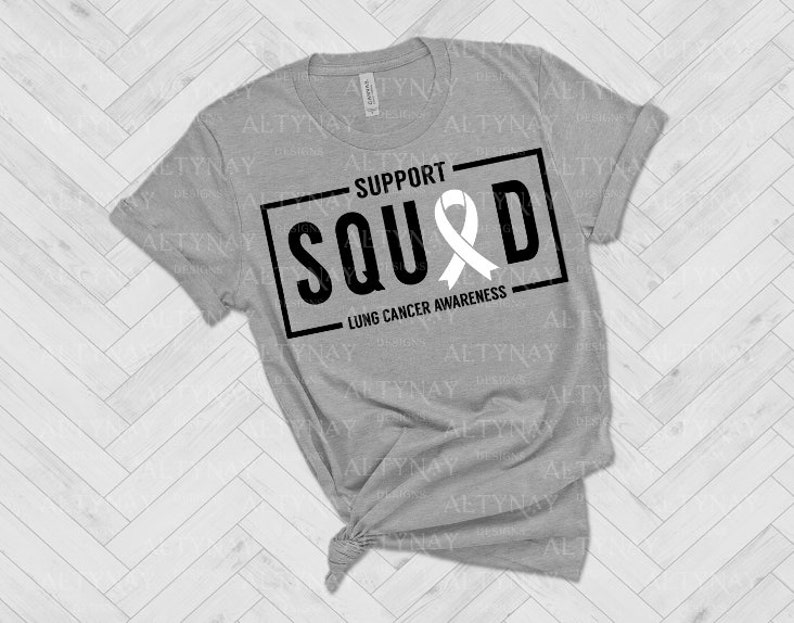 May include: Gray t-shirt with a black and white graphic that says "Support Squad" with a white ribbon and the text "Lung Cancer Awareness".