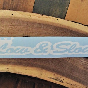 May include: White vinyl sticker with a crown and the text "Low & Slow" on a light blue background.