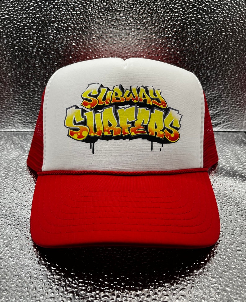 May include: A white and red trucker hat with a yellow and black graphic that says "Subway Surfers".