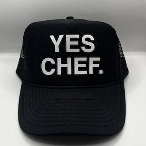 May include: Black trucker hat with a white mesh back and the text "YES CHEF." in white.