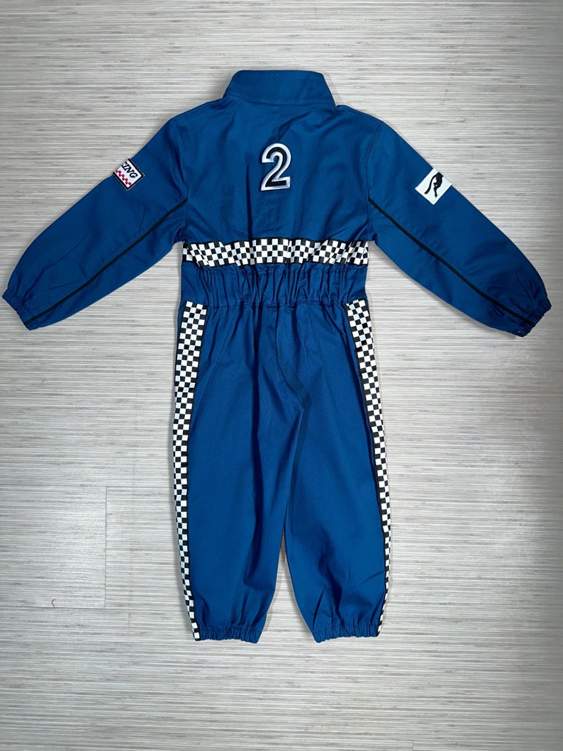 May include: Blue racing jumpsuit with black and white checkered accents. The jumpsuit has a zipper closure, a collar, and long sleeves. The back of the jumpsuit has a number "2" and a kangaroo logo.