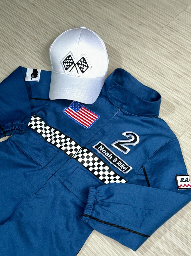 May include: Blue racing jumpsuit with a checkered belt, a white cap with checkered flags, an American flag patch, and the number 2 with the name "Noah B. RH#" on it.