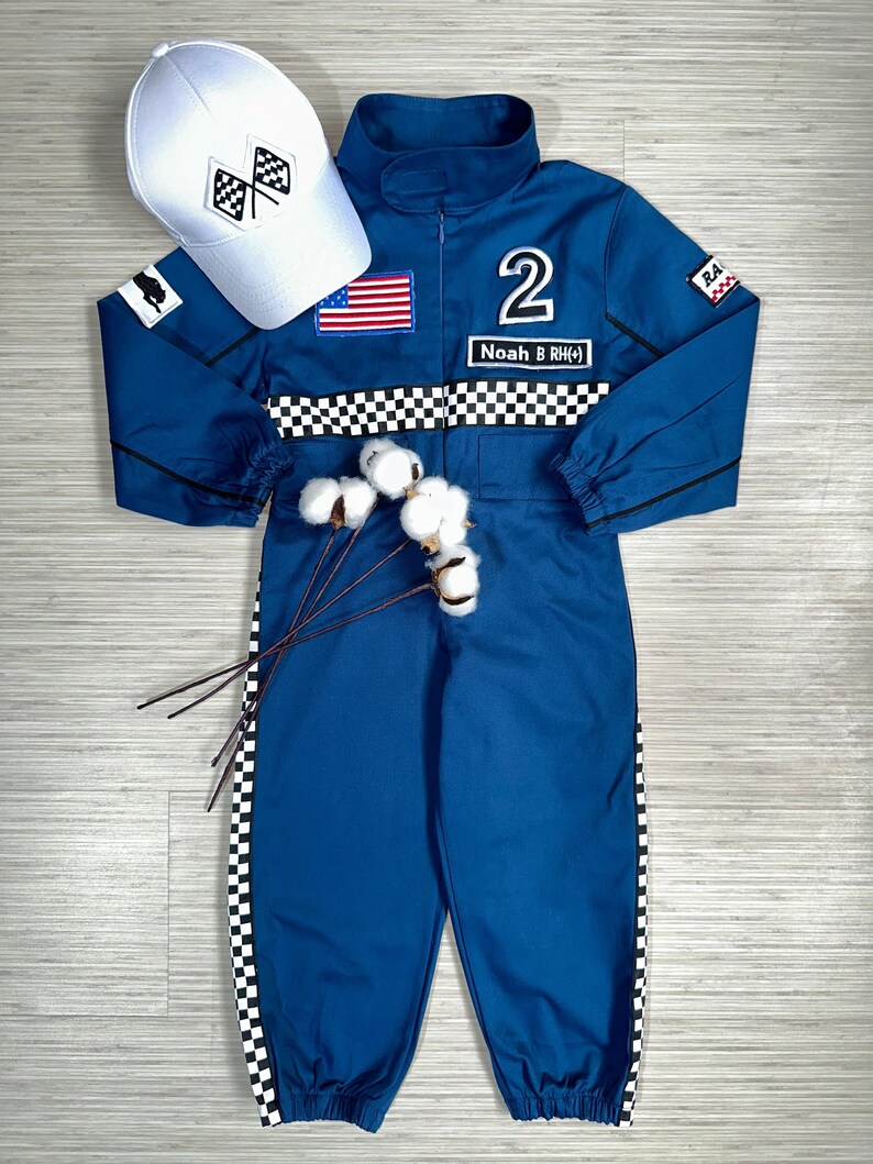 May include: Blue racing jumpsuit with black and white checkered trim, a white cap with a checkered flag design, and the name "Noah B RH#" on the front. The jumpsuit has an American flag patch and the number "2" on the chest.