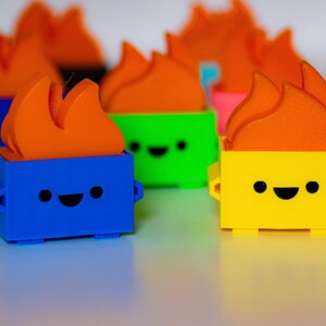 May include: A collection of colorful toy figurines with a flame design on top. Each figurine has a different colored body and a smiling face. The figurines are made of plastic and are approximately 3 inches tall.