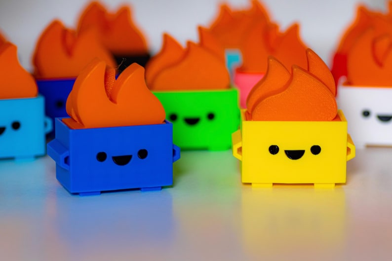 May include: A collection of colorful toy figurines with a flame design on top. Each figurine has a different colored body and a smiling face. The figurines are made of plastic and are approximately 3 inches tall.