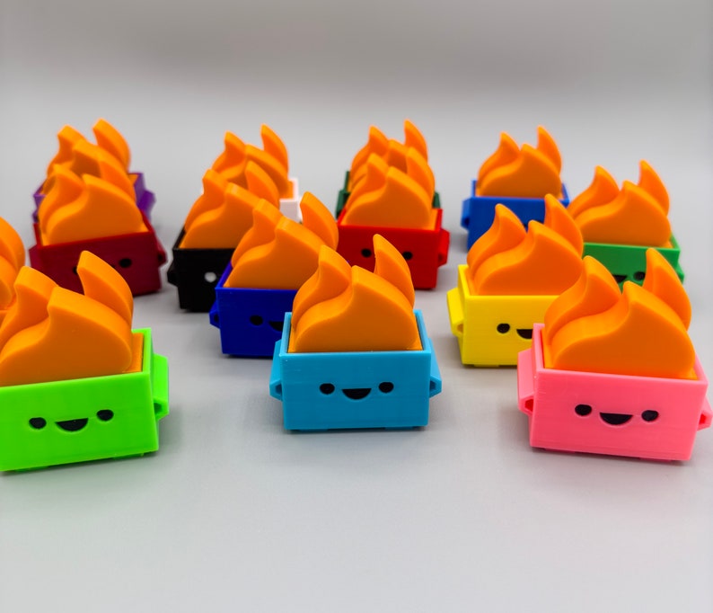 May include: A collection of colorful, small, fire-shaped figurines with happy faces. Each figurine is in a different color, including red, blue, green, yellow, and pink. The figurines are made of plastic and have a 3D design.