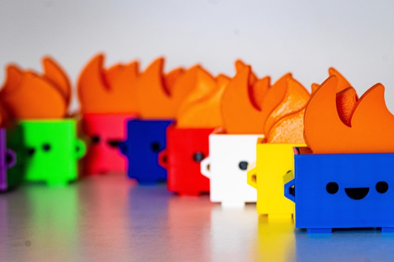 May include: A row of colorful toy trash cans with orange flames on top. Each trash can has a different color and a cute cartoon face.