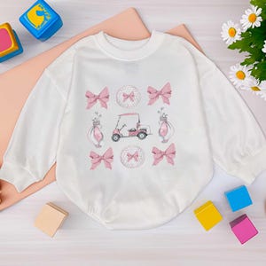 ピンクの女の子用ゴルフスウェットシャツ、女の子用かわいい幼児用ゴルフウェア、ゴルフカートとリボンのセーター、ゴルファーのママやパパの娘へのギフト