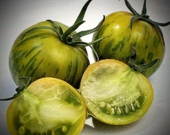 May include: Green and yellow striped tomatoes, some cut open to show the green flesh and seeds.