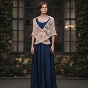 May include: A floor-length navy blue sleeveless dress paired with a light peach-coloured knitted shawl. The shawl features an open, airy, diamond-shaped lattice pattern and is draped over the shoulders, crossing at the front of the torso.