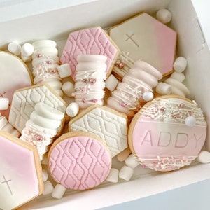 Peut inclure: Une bo&icirc;te cadeau blanche remplie de biscuits roses et blancs et de guimauves. Les biscuits sont d&eacute;cor&eacute;s de gla&ccedil;age rose et blanc et de p&eacute;pites. Un biscuit porte le nom "ADDY".