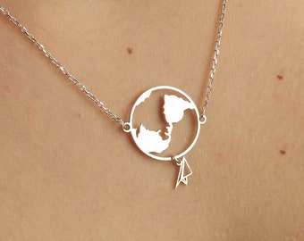 May include: A silver necklace with a delicate chain and a pendant shaped like a world globe with a paper airplane hanging from it.