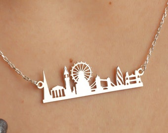Puede incluir: Un collar de plata con un colgante de la silueta de Londres. El colgante presenta el London Eye, el Big Ben y el Tower Bridge.