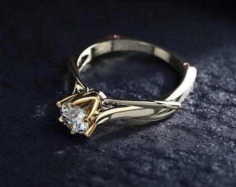 Peut inclure: Une bague de fiançailles en or et argent avec un gros diamant clair. La bague a un design de bande torsadée et un sertissage à quatre griffes. La bague est présentée sur une surface sombre et texturée.