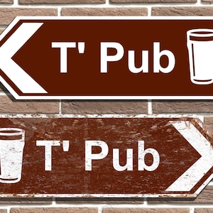 以下が含まれることがあります： 白い矢印と「T' Pub」という文字、白いシルエットのジョッキグラスが描かれた茶色の看板が2つ。上の看板は滑らかな表面で、下の看板は使い古された金属の表面です。